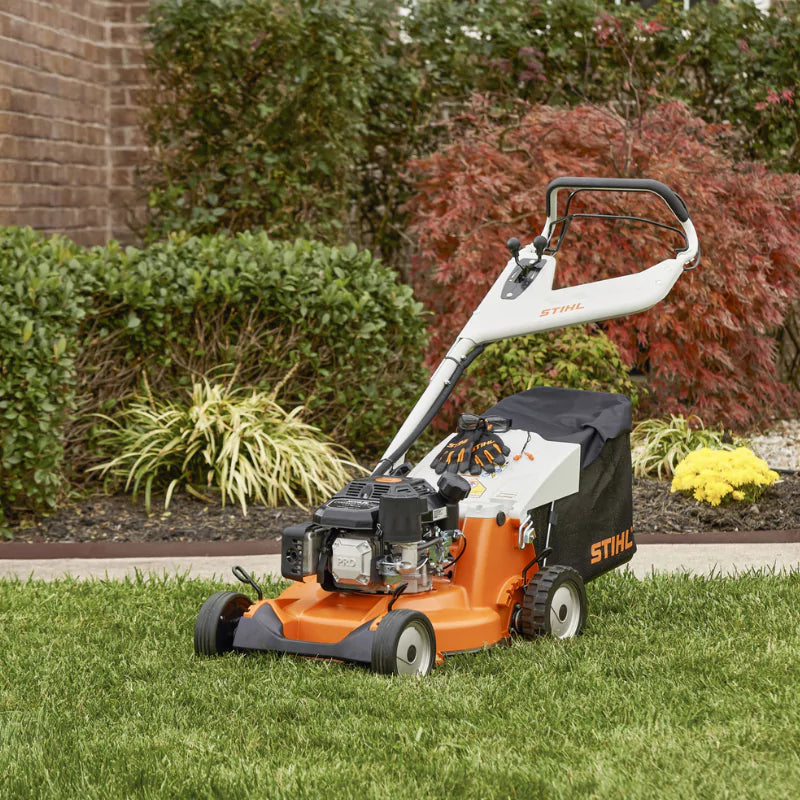 STIHL RM 756 YC Self-Propelled Lawn Mower in use on a manicured lawn with vivid autumn landscaping.